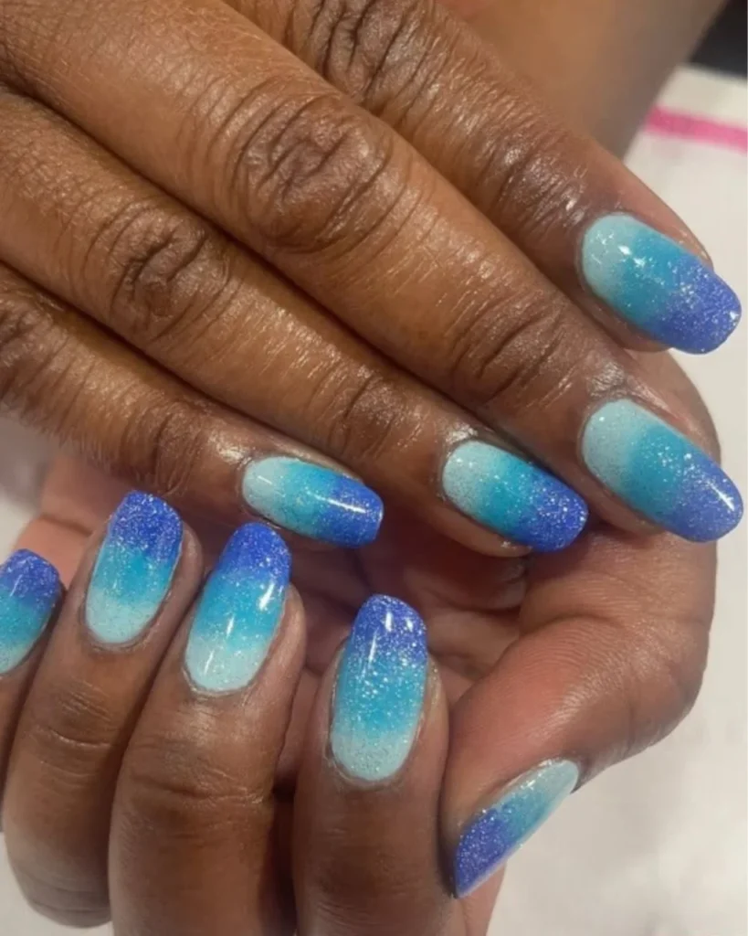 Blue and turquoise glitter ombre nails with a sparkling gradient on oval-shaped nails.