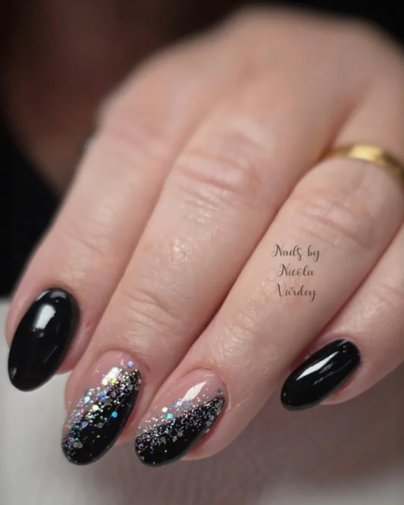 Black almond-shaped nails with holographic glitter ombre accents on a nude pink base