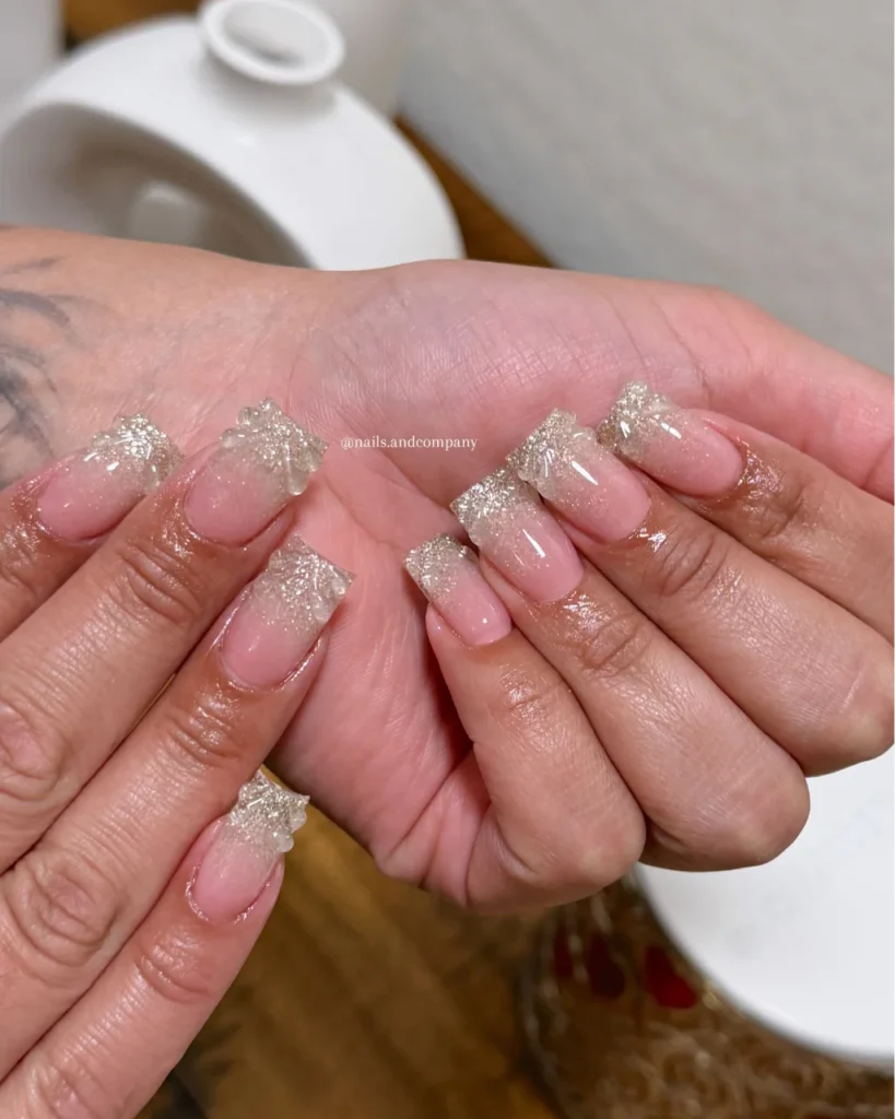 Christmas glitter ombre nails with a sheer nude-pink base fading into sparkling champagne gold glitter tips on square nails.
