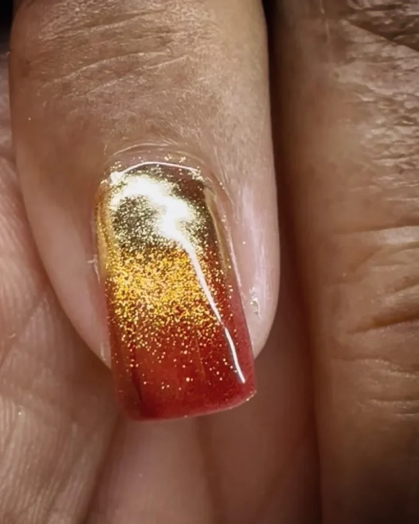 Christmas glitter ombre with gold glitter fading into deep red glitter on a glossy square-shaped nail.