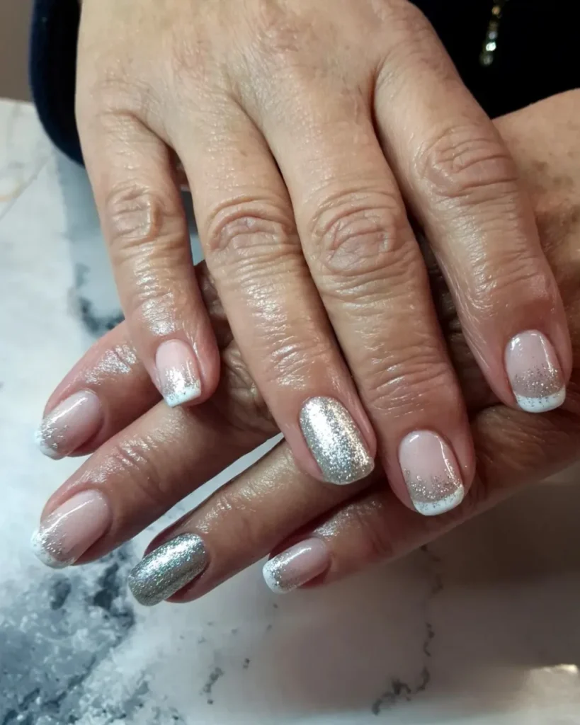 Christmas glitter ombre nails featuring a sheer pink base, silver glitter fades, white French tips, and full silver glitter accent nails.