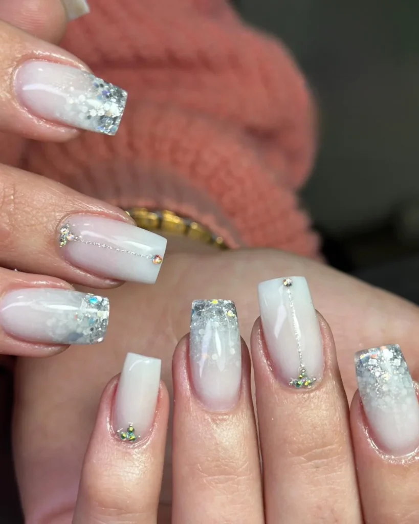 Christmas glitter ombre featuring a milky white base, silver glitter tips, and delicate rhinestone accents on square and almond nails.