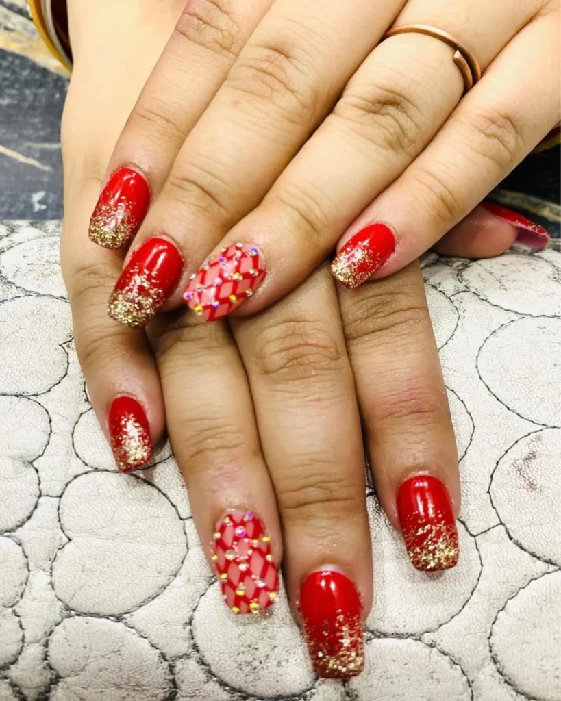 Classic red Christmas nails with gold glitter ombre tips and jeweled red accent nails.