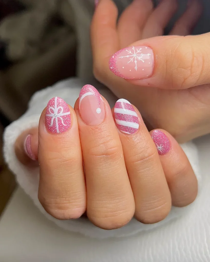 Classy Christmas short nail designs featuring pink glitter polish, white gift-wrap bows, candy-cane stripes, and delicate snowflake nail art on a nude pink base.