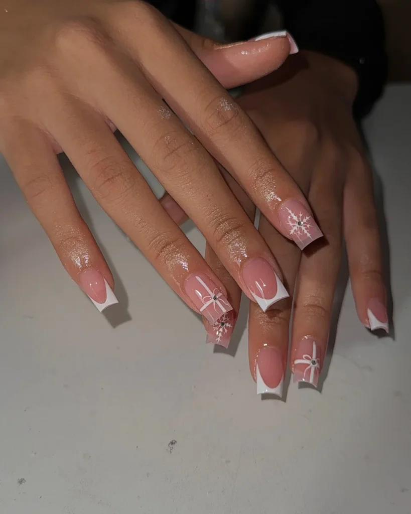 French manicure Christmas nail designs with glossy pink square nails, white French tips, delicate white gift bows, and sparkling snowflake accents.