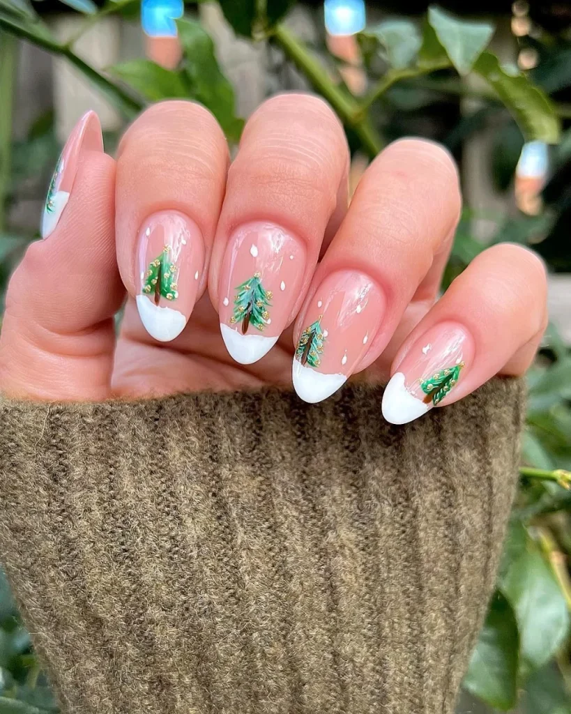 French manicure Christmas nail designs with sheer pink nails, white French tips, green Christmas trees, and delicate gold accents.
