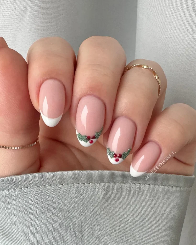 French manicure Christmas nail designs with glossy pink nails, white French tips, green glitter accents, and tiny red holly berries.