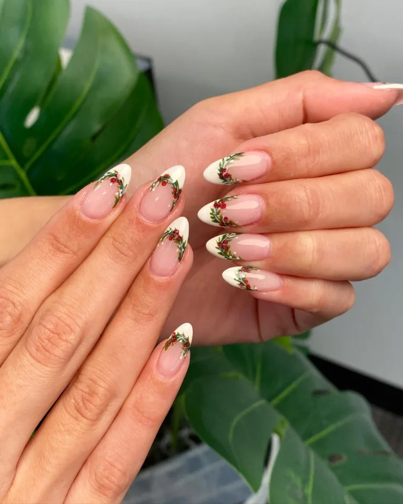 French manicure Christmas nail designs with a sheer pink base, white almond French tips, delicate green holly leaves, and tiny red berries.
