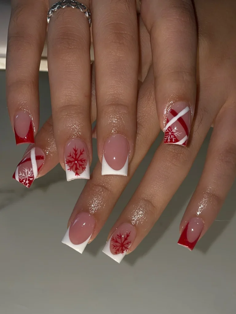 French manicure Christmas nail designs with nude pink nails, red and white French tips, and delicate red snowflake nail art.