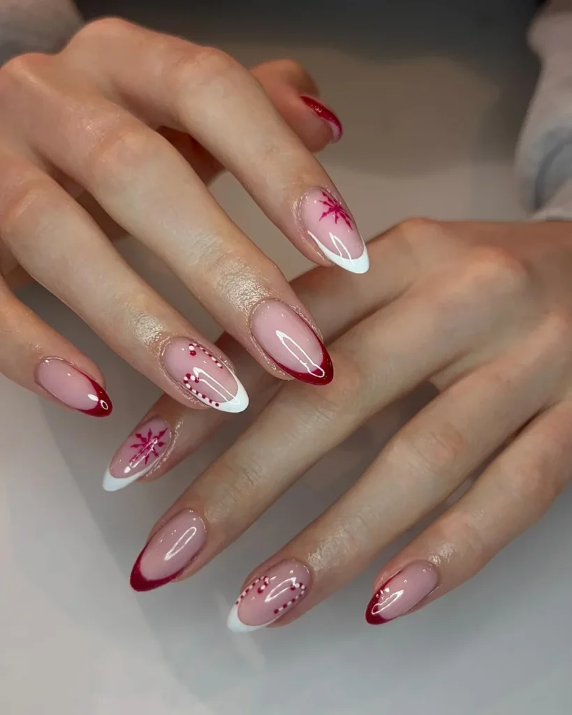 French manicure Christmas nail designs featuring pink almond nails, burgundy and white French tips, red snowflakes, and delicate dotted accents.