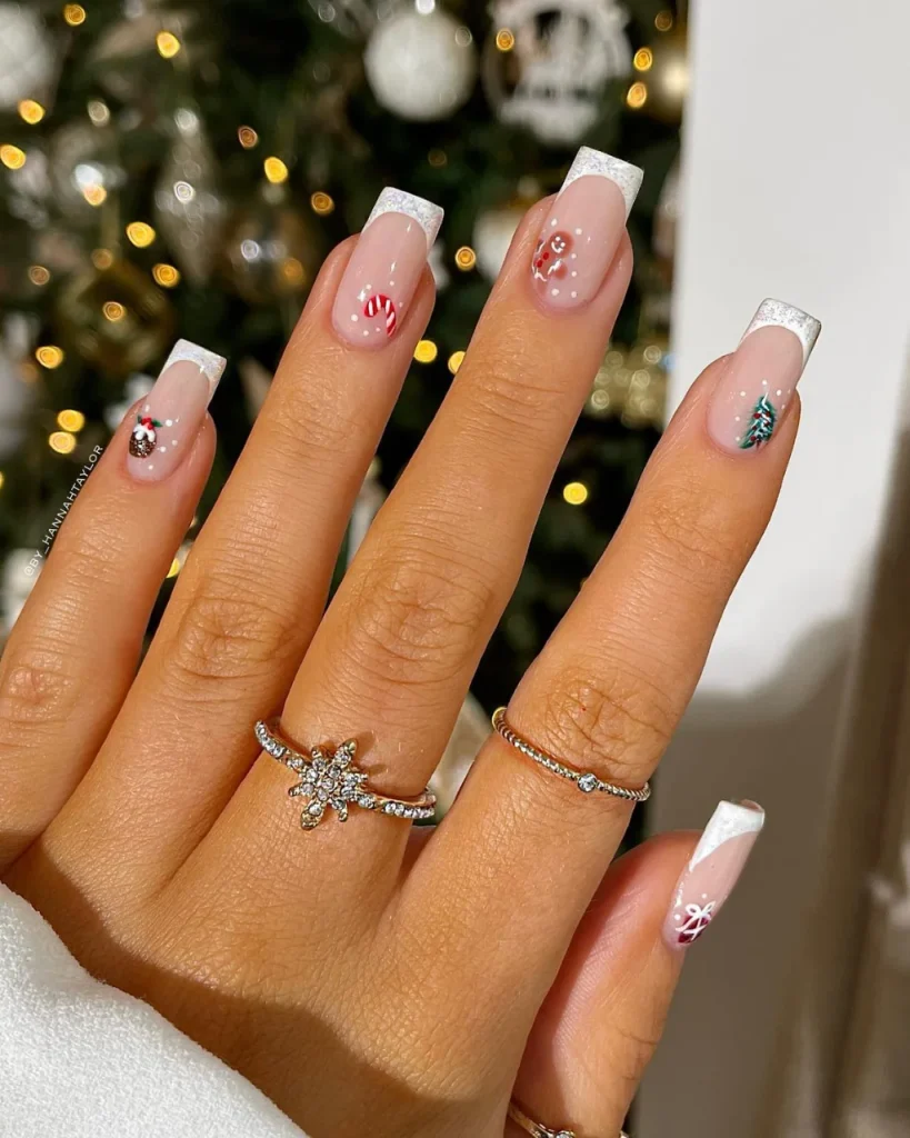 French manicure Christmas nail designs with nude pink nails, silver glitter French tips, candy cane art, Christmas trees, and festive white details.