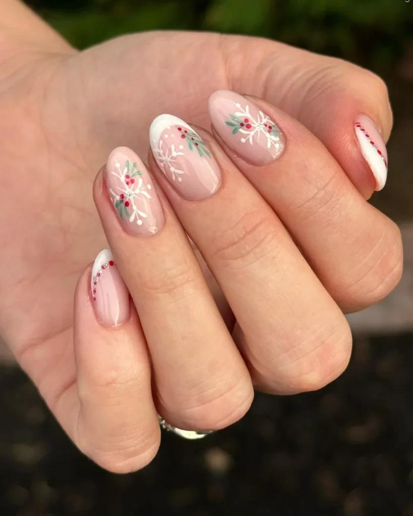 French manicure Christmas nail designs with sheer pink nails, white French tips, delicate white snowflakes, green foliage, and tiny red berries.