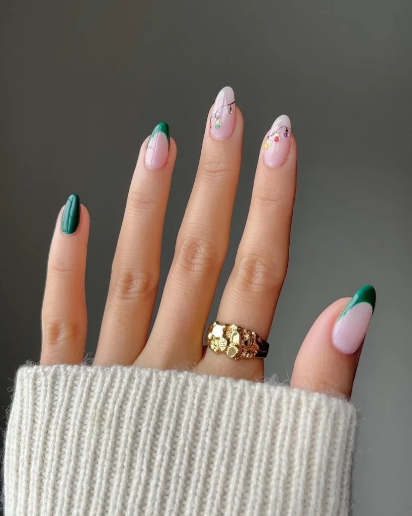 Green Christmas French tip nail designs with deep green tips, a sheer pink base, and delicate multicolored Christmas light nail art.