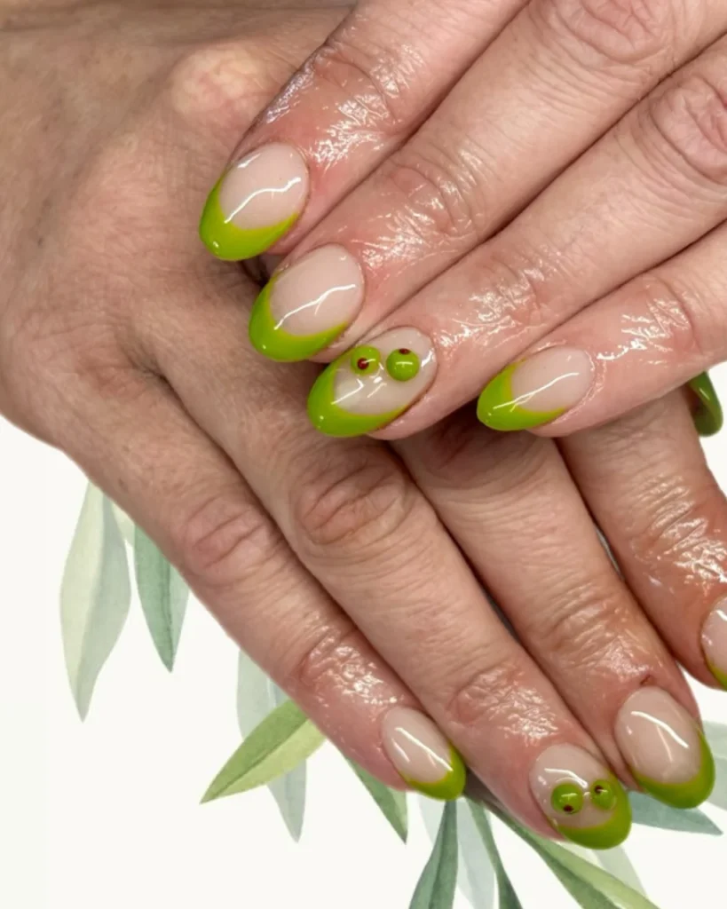 Green Christmas French tip nail designs with bright lime green tips, a nude pink base, and tiny green berry accents with red centers.