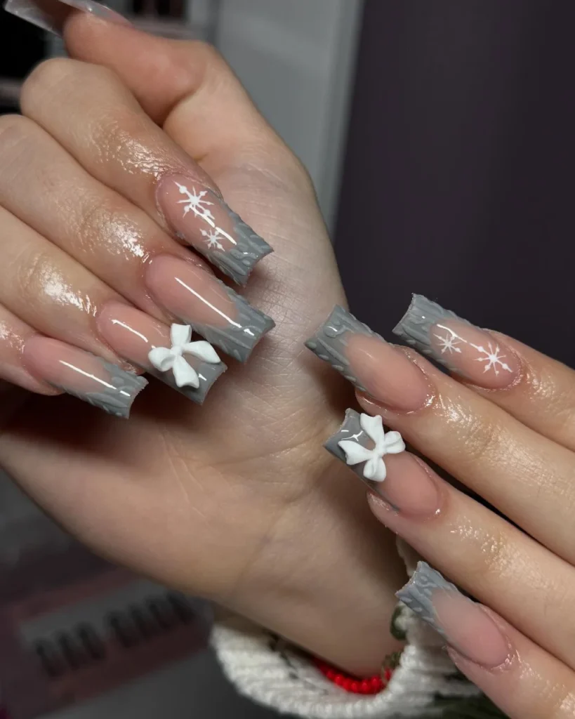 Green Christmas French tip nail designs with textured gray-green tips, white snowflakes, and 3D bows on nude pink square nails.