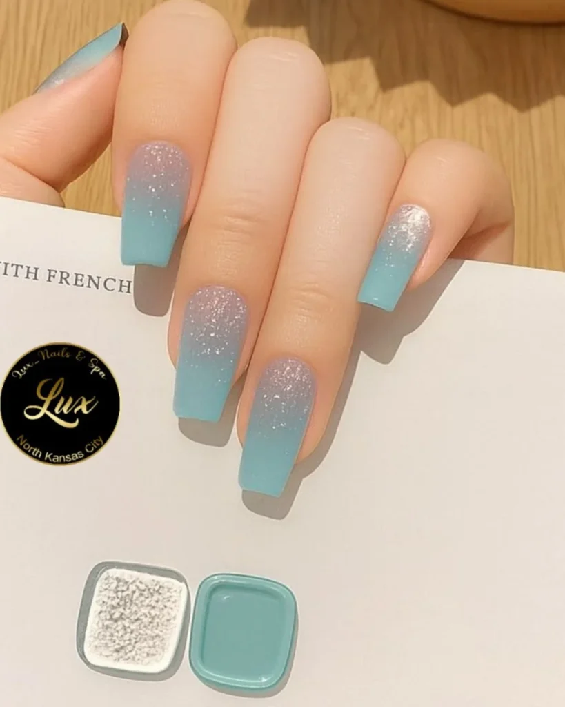 Christmas glitter ombre nails featuring icy blue tips fading into a soft grey base with sparkling silver glitter on long square nails.