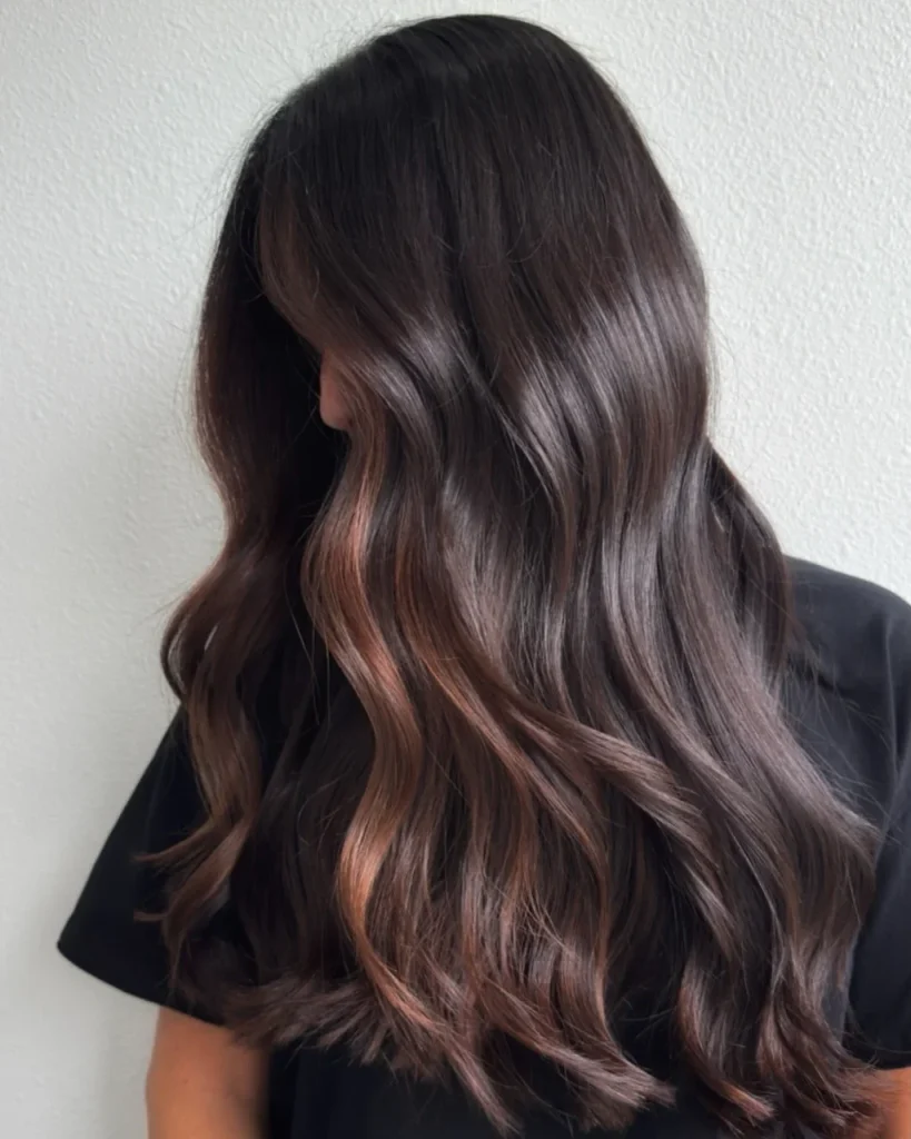 Milk chocolate balayage on dark brown hair with warm caramel highlights and glossy, long waves