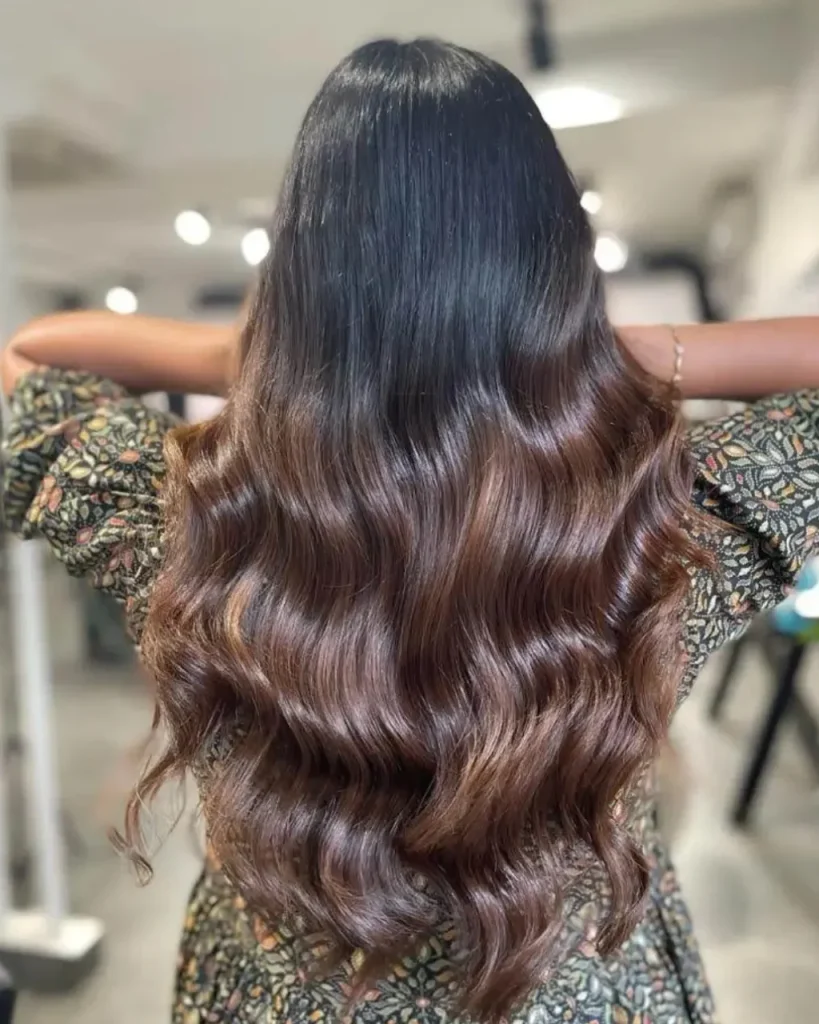 Light chocolate brown hair color with a soft sombre melt, darker roots, warm brown lengths, and long glossy waves