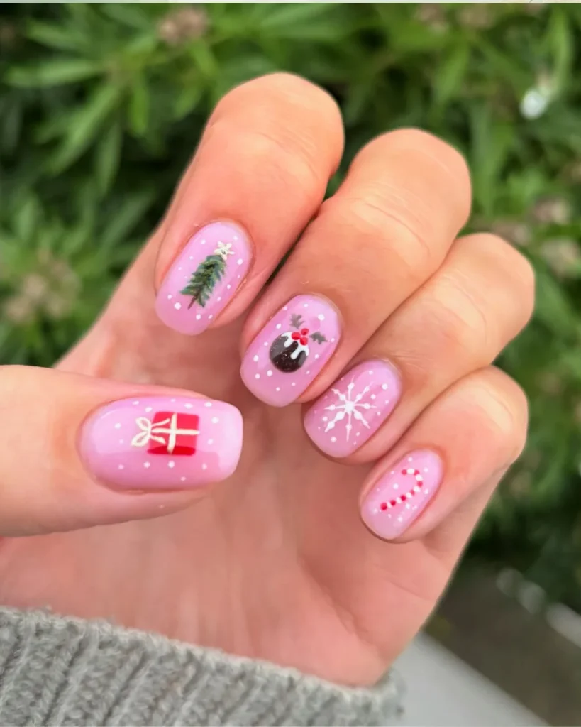 Light pink Christmas nails featuring cute mix-and-match holiday designs, including tiny Christmas trees, snowflakes, candy canes, and wrapped presents.