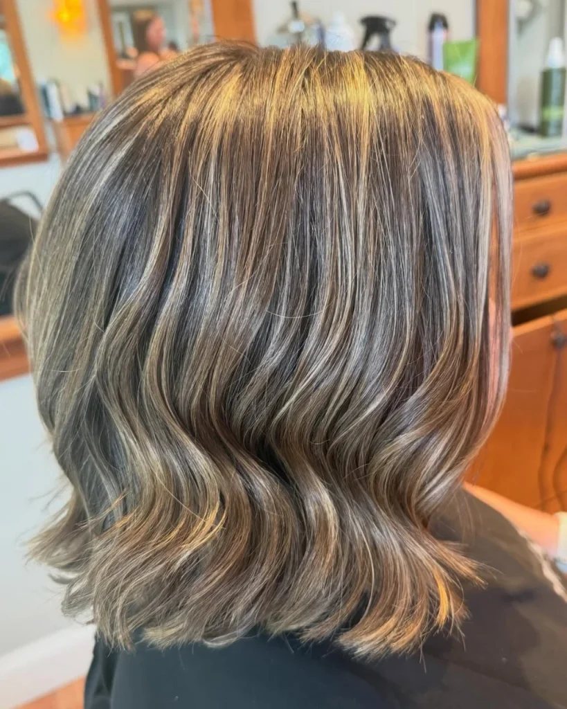 Medium length  with golden butterscotch highlights, cool brown tones, and soft layered waves.