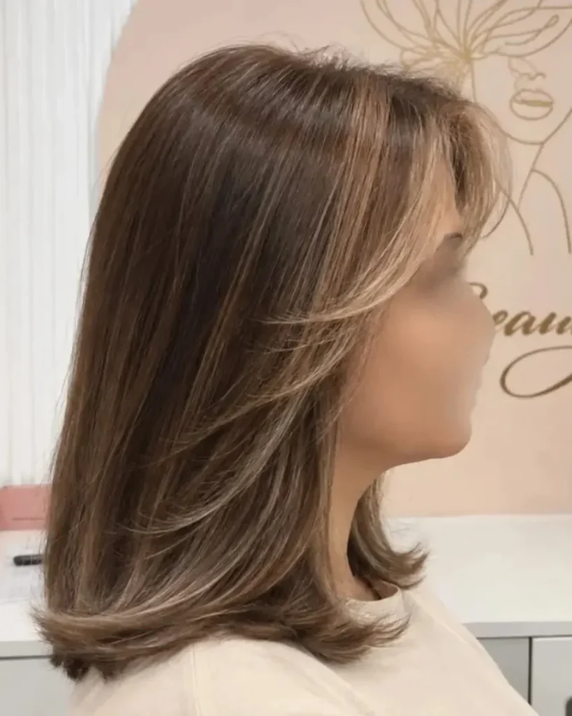 Medium length light brown hair with mocha tones, face-framing highlights, and softly flipped layers.