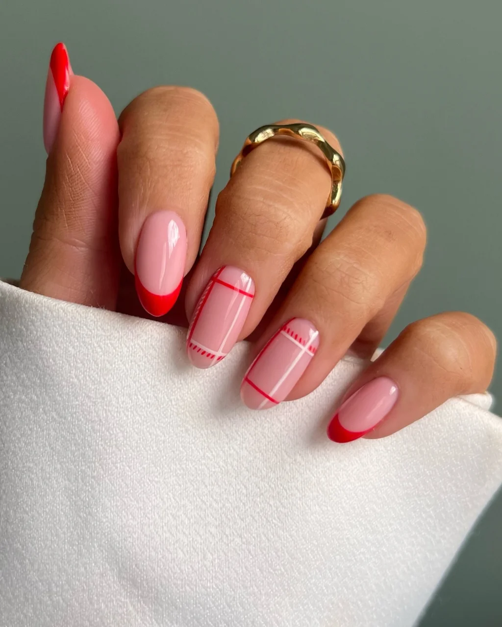 Red French tip Christmas nail designs featuring glossy pink nails, vibrant red tips, and delicate red and white plaid-inspired line patterns for a modern festive manicure