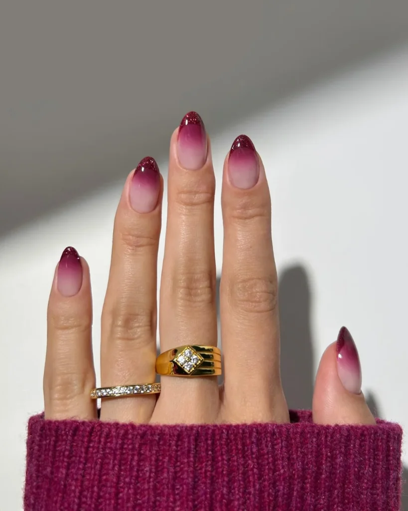 Red Glitter Ombre French Tips fading from nude pink to sparkling berry-red on elegant almond-shaped nails.