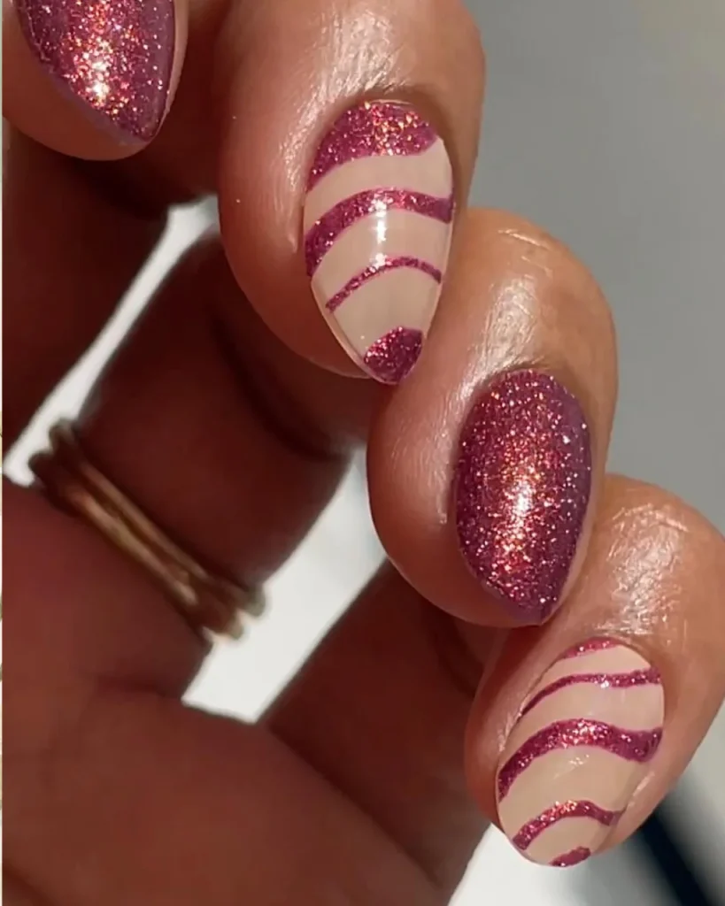 Shimmering pink Christmas nails with a translucent pink base, fine golden shimmer, and elegant metallic accents.