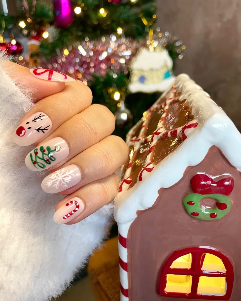 Short Christmas press-on nail designs featuring nude pink nails with candy canes, a reindeer face, green Christmas lettering, and white snowflakes.