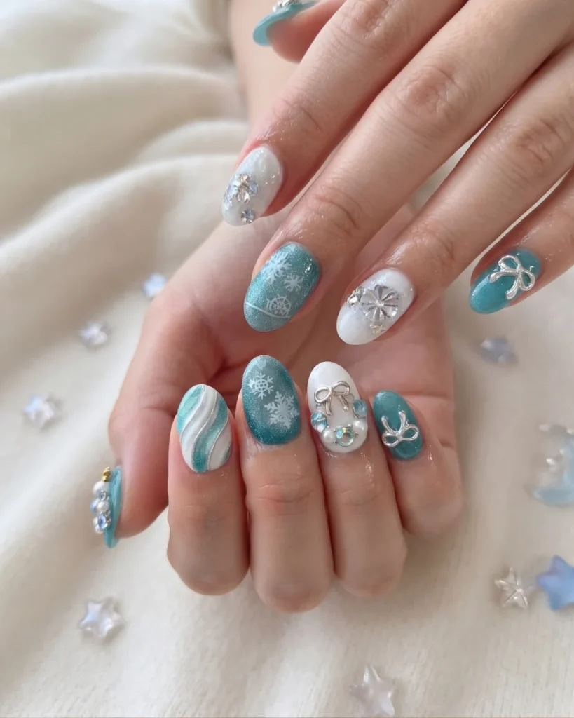 Short Christmas press on nail designs featuring icy teal glitter, white snowflakes, silver bows, and sparkling rhinestone accents.