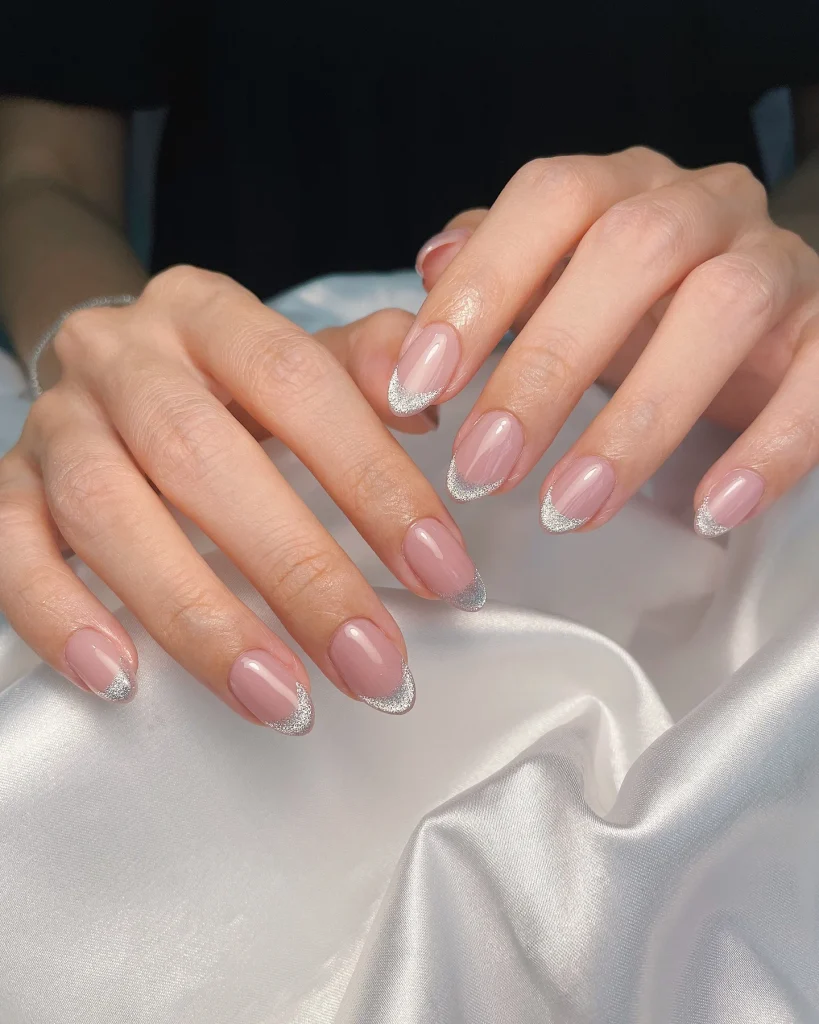 Short French Tip Christmas Nail Designs featuring elegant pink nails with delicate silver glitter French tips.