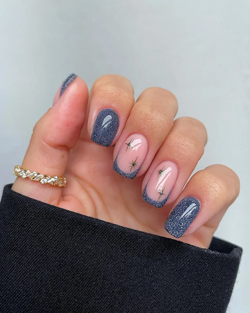Short french tip christmas nail designs featuring navy blue glitter nails, blush pink nails with navy French tips, and delicate gold starburst accents, a festive variation of white french tip christmas nail designs.