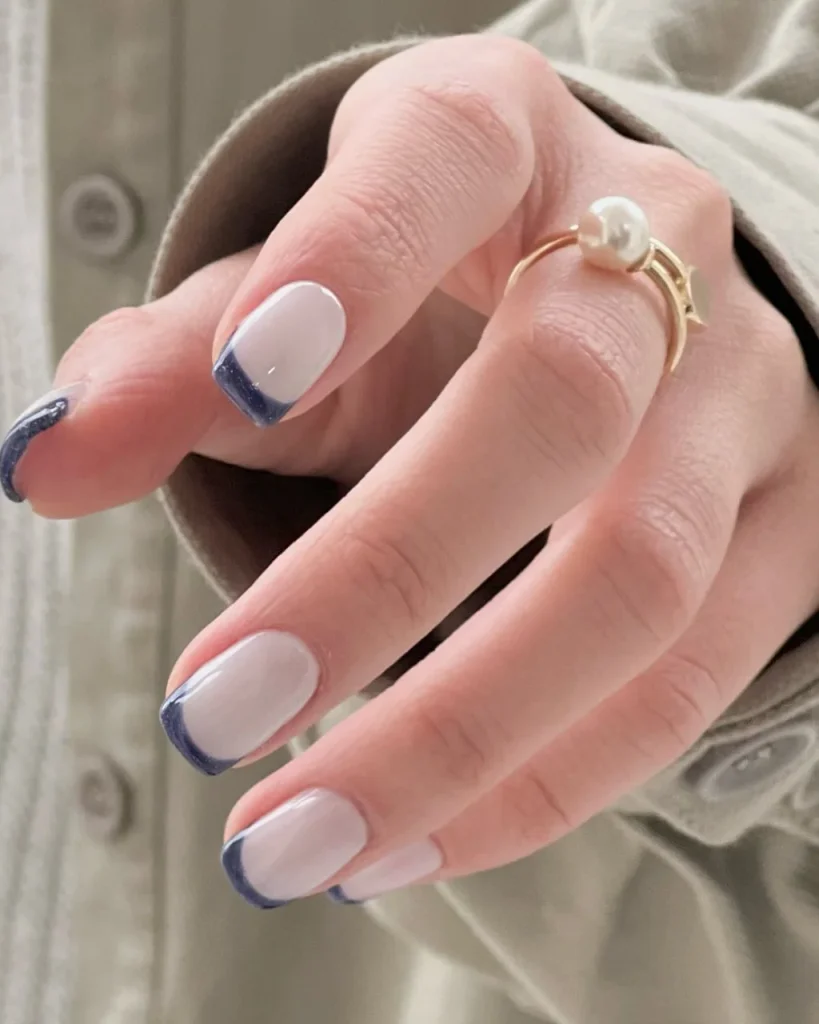 Short french tip christmas nail designs with a sheer milky pink base and elegant navy blue French tips on short square nails.