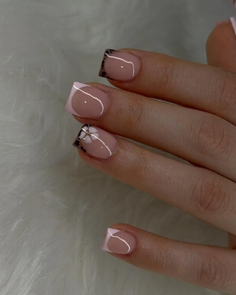 Short french tip christmas nail designs featuring dusty pink square nails, pale pink French tips, delicate white curved lines, black dotted accents, and a small white bow detail, offering a creative variation of white french tip christmas nail designs.
