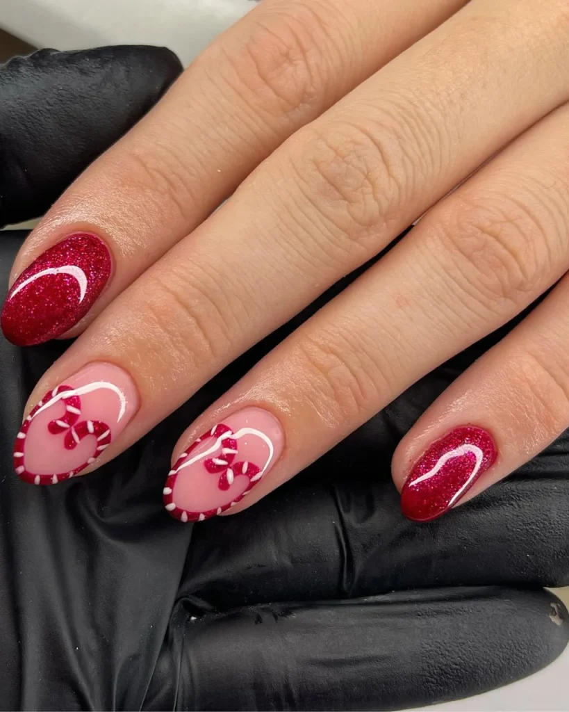 Short french tip christmas nail designs featuring pink nails with red and white candy cane heart tips, deep red glitter accent nails, and delicate white curved lines, a festive alternative to white french tip christmas nail designs.
