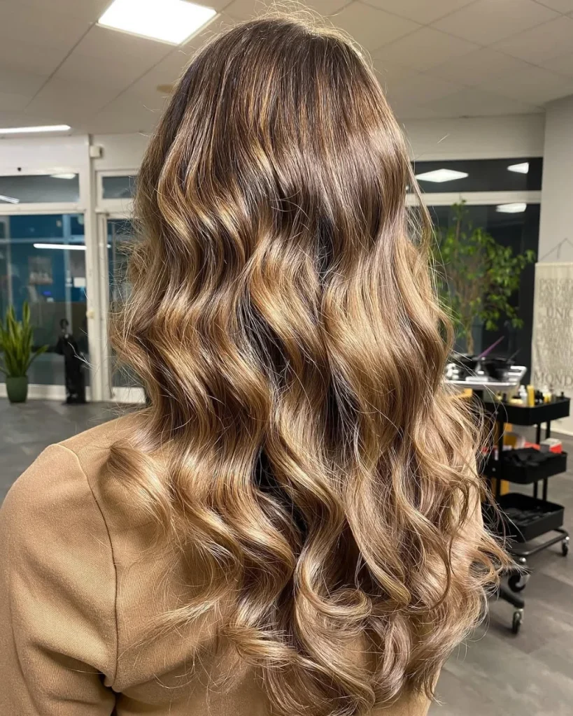 Warm honey brown balayage with golden brown highlights, caramel tones, and soft beach waves for a natural sun-kissed brunette look