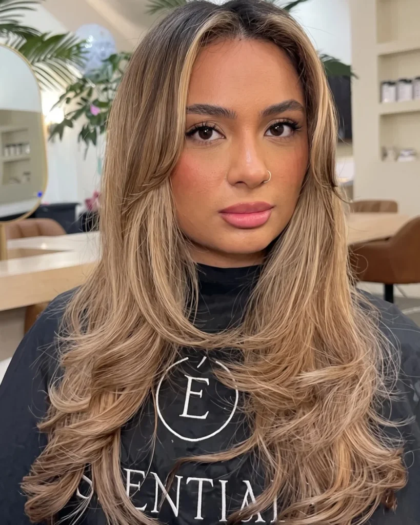 Warm honey brown hair balayage with bronze highlights, bright face-framing pieces, and long layered waves