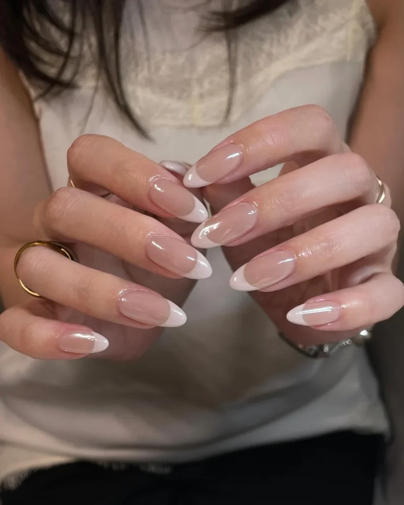 Elegant white french tip Christmas nail designs with a sheer pink base and glossy almond-shaped nails.
