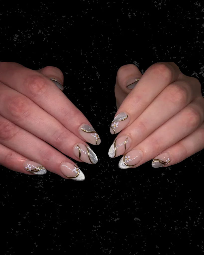 White french tip christmas nail designs with pearly silver tips, gold swirls, and delicate white floral accents on pink nails.